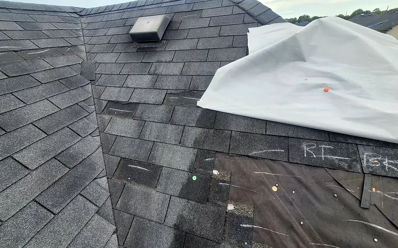 Roof repair area with temporary sheet covering part of the shingles